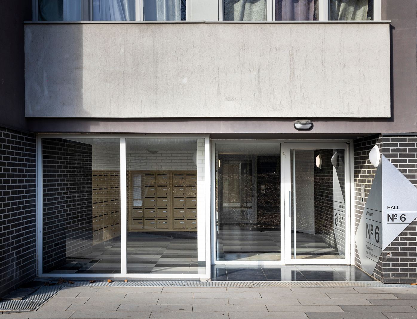 Signalétique intérieure sur mesure dans une résidence parisienne arborée avec intégration harmonieuse et design graphique moderne.