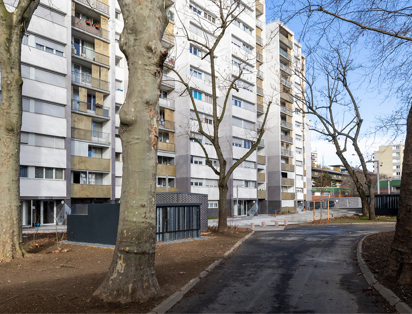 Vue d’ensemble des entrées d’immeubles avec signalétique intérieure sur mesure dans une résidence parisienne arborée.